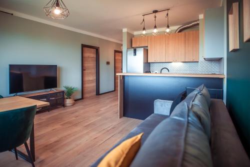 a living room with a couch and a table and a kitchen at SECOND HOME Lubawa - 3 pokoje, 5 łóżek, Netflix i Max, parking, winda in Lubawa