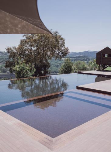an infinity pool with a view of a house at Medronho D'Ouro bungalows in Foz do Sousa