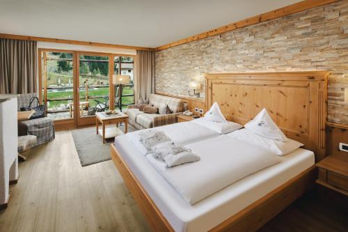 a bedroom with a large white bed with a brick wall at Cyprianerhof Dolomit Resort in Tires