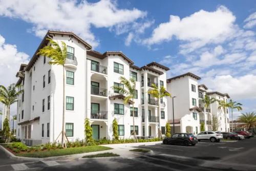 a large white apartment building with cars parked in a parking lot at Miramar 2BR w Gym Pool WD nr WF MIA-70 in Miramar