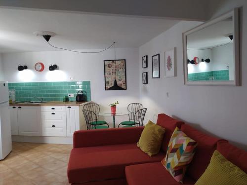 sala de estar con sofá rojo y cocina en Casa con piscina cerca de Sevilla, en Carrión de los Céspedes