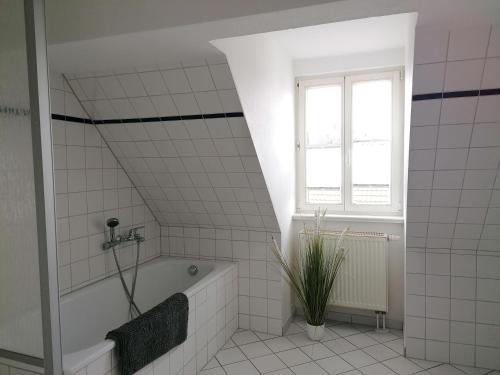 a white tiled bathroom with a tub and a window at Ferienwohnung Neuer Weg 15 in Quedlinburg