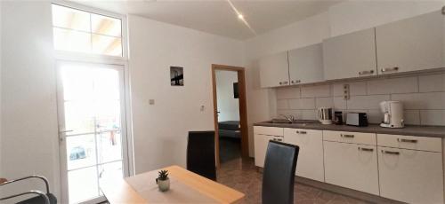 a kitchen with white cabinets and a table and a window at Apartment für bis zu 6 Personen mit Balkon in Halberstadt