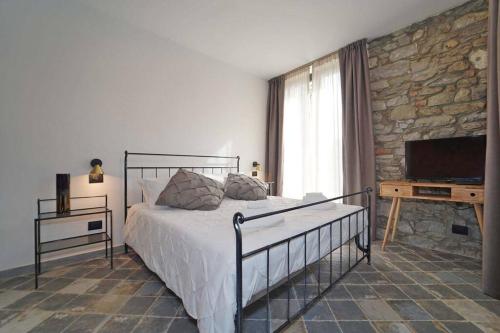 a bedroom with a bed and a tv and a stone wall at Villa Viola 12 pax family retreat pool near 5Terre in Aulla