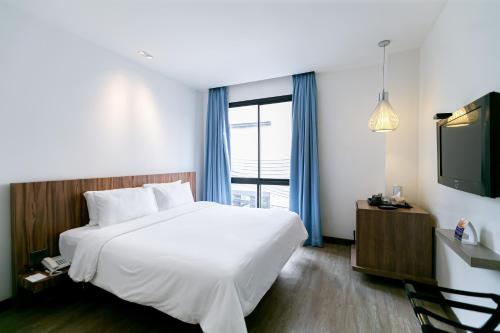 um quarto de hotel com uma cama e uma televisão em Uno Express (SHA) em Bangkok