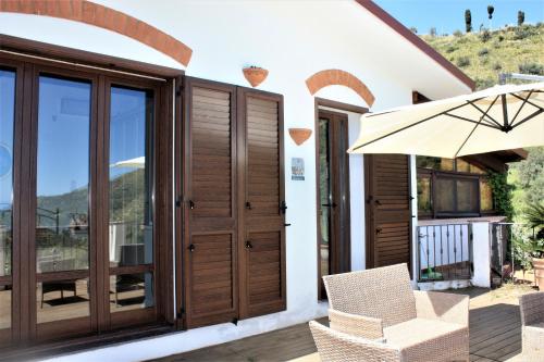 a house with wooden doors and a balcony with an umbrella at La Finestra sulle Eolie in Reitano