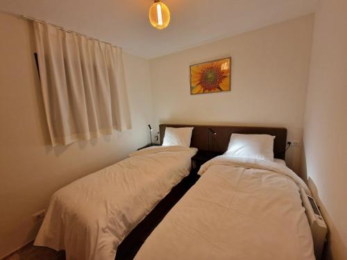 Duas camas num pequeno quarto com uma janela em Les Papillons du Ventoux - L'Aurore de Provence - twee slaapkamerappartement met terras en tuin em Malaucène