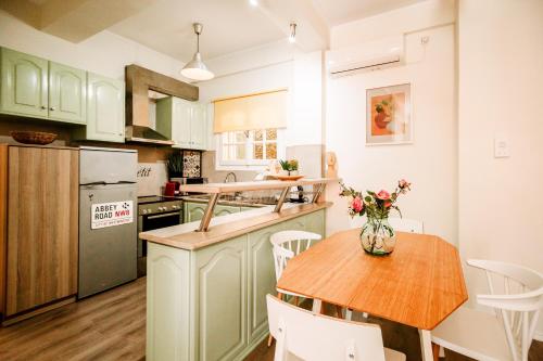 a kitchen with green cabinets and a wooden table at Melos House - Charming Apartment with Jacuzzi in the Heart of the City Perfect for Memorable Summer Experiences By Villa Mana Gers in Zakynthos Town