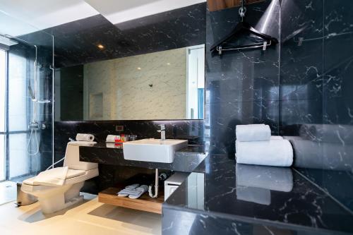 een badkamer met een wastafel, een toilet en een spiegel bij Uno Express (SHA) in Bangkok