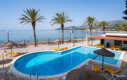 una piscina con palmeras y el océano en Medplaya Hotel Vistamar Costa Dorada, en Hospitalet de l'Infant