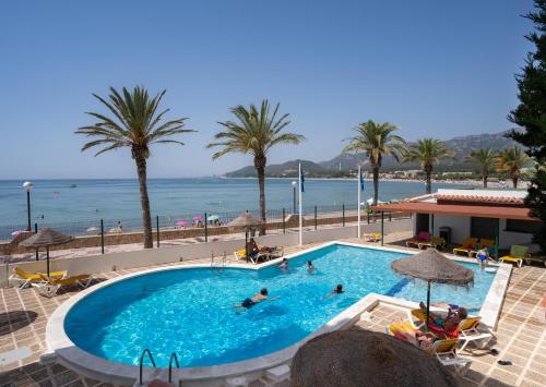 a swimming pool with palm trees and the ocean at Medplaya Hotel Vistamar Costa Dorada in Hospitalet de l'Infant