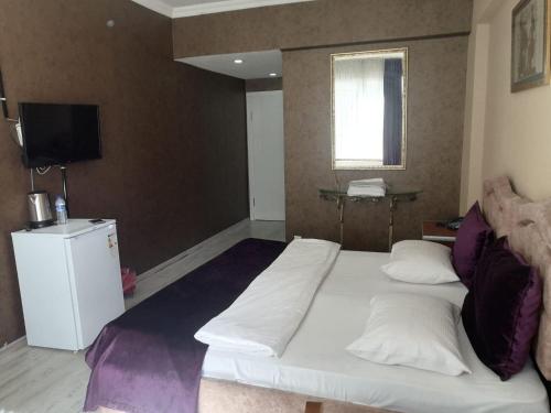 a bedroom with a large white bed and a television at Masal Otel in Kocaeli