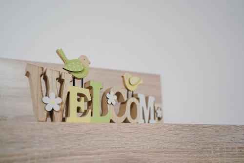 a wooden sign with a bird and the word welcome at Pri Neji in Postojna