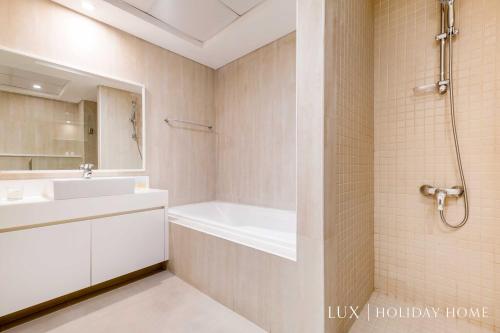 a bathroom with a white tub and a sink at LUX The JBR Beach Sea View Suite in Dubai