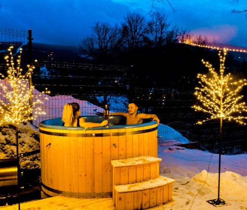 a man and woman in a hot tub in the snow at Apartamenty Larice - balia lub sauna sesja gratis ten weekend, morsowanie w basenie in Świeradów-Zdrój