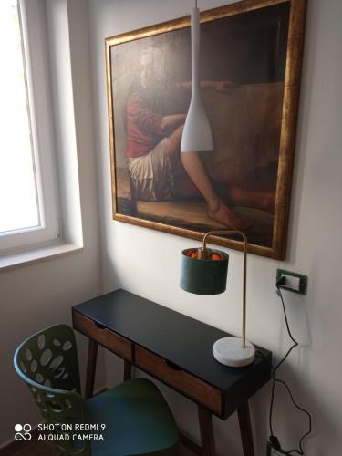 a desk with a lamp and a painting on the wall at Boutique Hotel Ferrara in Ferrara