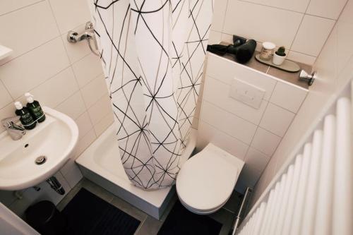 Baño blanco con aseo y lavamanos en Sanierter Altbau, 2 Zimmer, 24-7 Check-in en Kiel