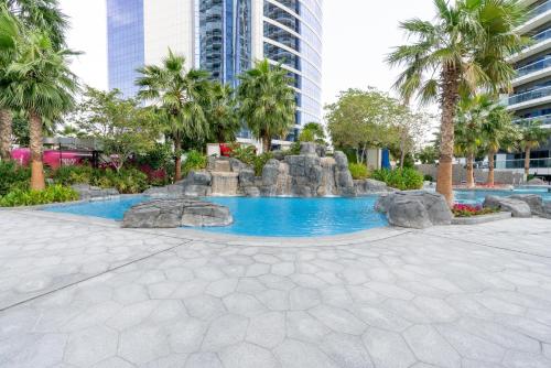 een fontein in een park met palmbomen en gebouwen bij GLOBALSTAY DAMAC Towers by Paramount in Business Bay in Dubai