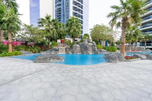 a fountain in a park with palm trees and buildings at GlobalStay DAMAC Towers by Paramount Business Bay Apartments in Dubai