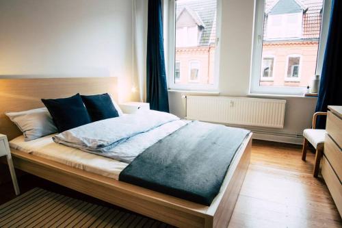 a bed in a bedroom with a large window at Sanierter Altbau, 2 Zimmer, 24-7 Check-in in Kiel