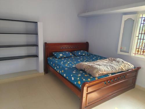 a bedroom with a wooden bed with blue sheets at SM GARDENS Luxury Homestay in Oothu