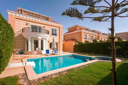 a villa with a swimming pool in front of a house at Selena Bay Resort & Beach Club in Hurghada