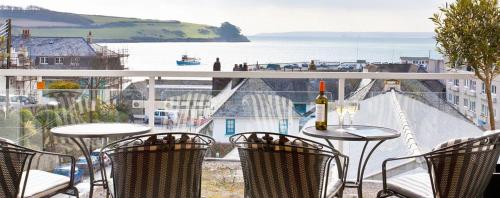 a balcony with tables and chairs and a view of the water at Shellseekers in Saint Mawes