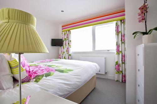 a bedroom with a bed and a lamp and a window at Shellseekers in Saint Mawes