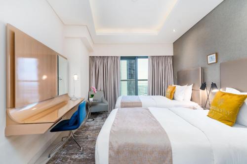 a hotel room with two beds and a desk at GlobalStay DAMAC Towers by Paramount Business Bay Apartments in Dubai