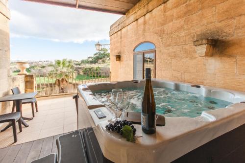 uma banheira de hidromassagem com uma garrafa de vinho em Centre Island Gozitan Farmhouse & Pool - Happy Rentals em Kerċem