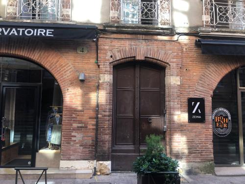 um edifício de tijolos com uma grande porta castanha em Appartement de prestige – rue des Arts em Toulouse