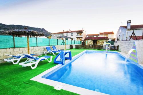 uma piscina com cadeiras e um guarda-sol e a água em El Robledillo em Robledillo