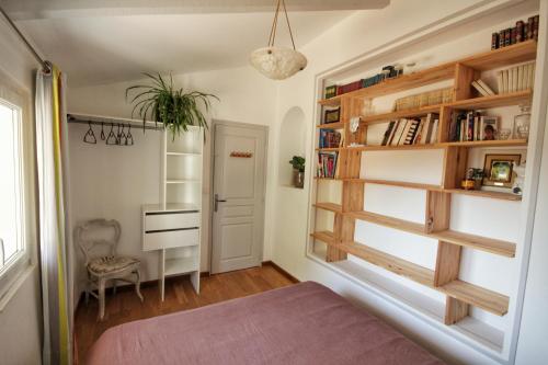 Zimmer mit einem Bett und einem Bücherregal in der Unterkunft Le Jardin Suspendu Gîte avec piscine et jacuzzi pour 15 personnes in Vailhauquès