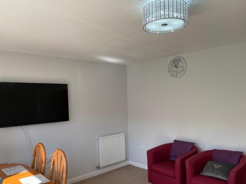ein Wohnzimmer mit 2 roten Stühlen und einem Flachbild-TV in der Unterkunft Newbuild - 3 bedrooms, 2 baths,5 mins from airport in Edinburgh