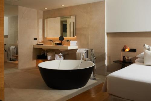 a bathroom with a bath tub next to a bed at Nakar Hotel in Palma de Mallorca