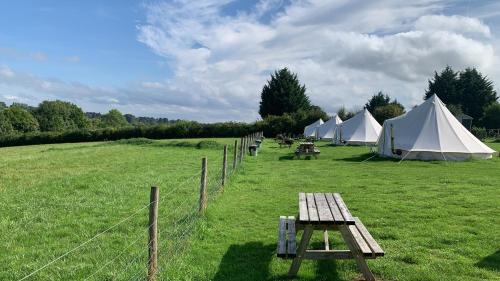 a group of tents in a field with a picnic table at Home Farm Radnage Glamping Bell Tent 5, with Log Burner and Fire Pit in High Wycombe