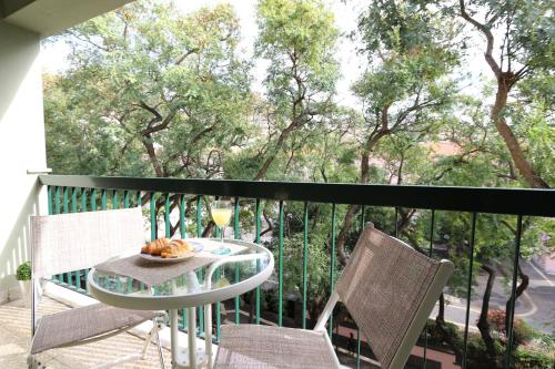 una mesa y sillas en un balcón con vistas a los árboles en Flat with Balcony at Downtown by Farmers Market, en Santa Luzia
