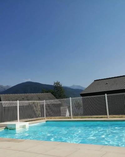 a swimming pool with a fence and mountains in the background at Appartement A proximité d'Ax les thermes in Ignaux