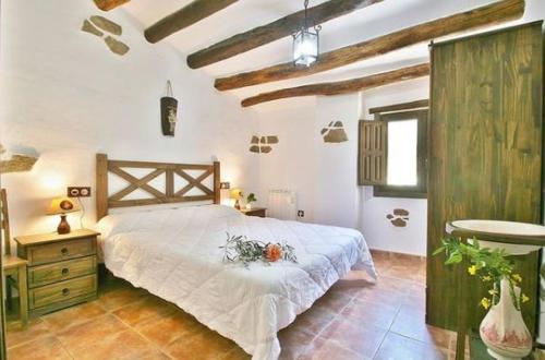 Un dormitorio con una cama grande en una habitación con techos de madera. en Molino Laroya, en Laroya
