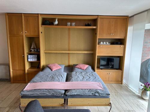 a bedroom with a bed and wooden cabinets at Appartment 2015 in Tossens in Tossenserdeich