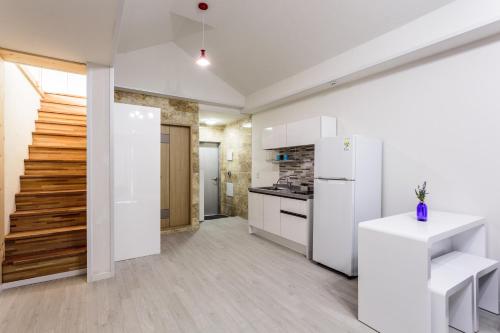 a kitchen with a white refrigerator and a staircase at Jeju Turning point Pension in Seogwipo