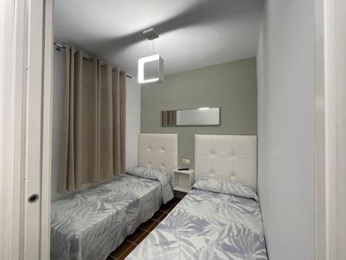 サアラ・デ・ロス・アトゥネスにあるApartamento en Atlanterra, Zahara de los Atunesのベッド2台と鏡が備わる客室です。