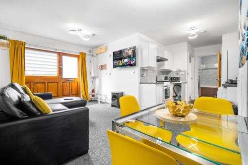 ein Wohnzimmer mit einem Glastisch und gelben Stühlen in der Unterkunft BROADWAY SUITE - Newly refurbished stylish apartment with FREE PRIVATE PARKING - Great location in Birmingham