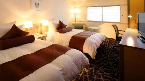 新潟市にあるANAクラウンプラザホテル新潟のベッド2台とテレビが備わるホテルルームです。