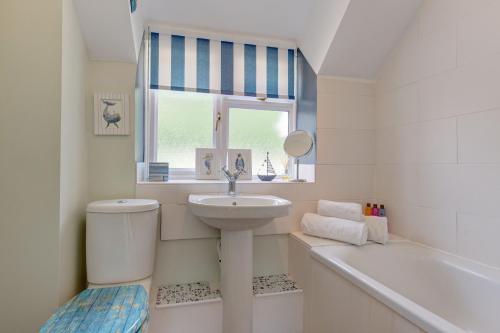 a bathroom with a sink and a tub and a toilet at Flint Cottage in Stiffkey