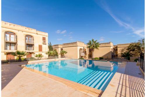 una gran piscina frente a un edificio en Harbour Views Gozitan Villa Shared Pool - Happy Rentals, en Mġarr