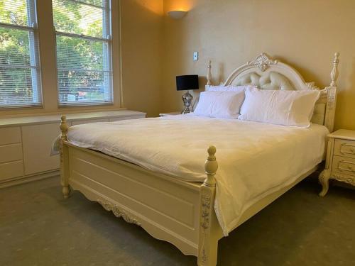 um quarto com uma grande cama branca com almofadas brancas em The Captain's Manor - Great location! em Corowa