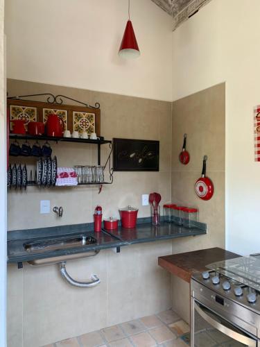 a kitchen with a counter with red pots and pans at Chalés Cores da Mata in Tiradentes