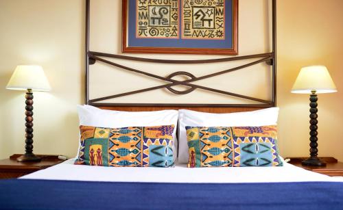 a bedroom with a bed with two lamps and two pillows at Pestana Rovuma in Maputo