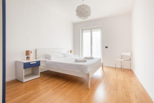 a white bedroom with a bed and a desk at Appartamenti Gabry in Riva del Garda